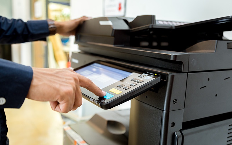A person using a multifunction office copier for document management. A person using a multifunction office copier for document management.