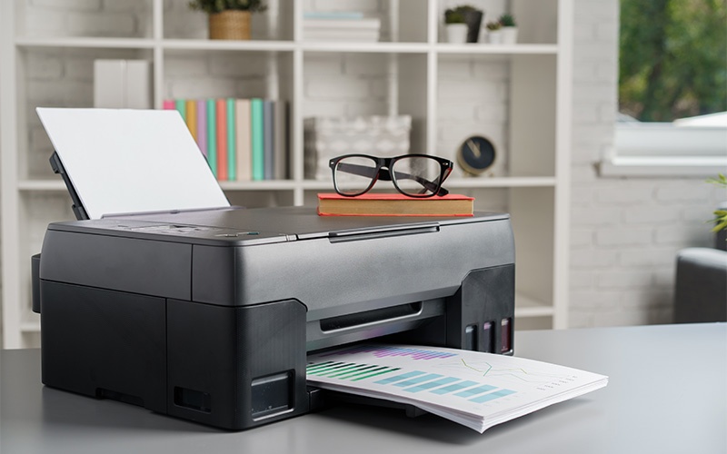 Office printer printing documents on a desk Office printer printing documents on a desk