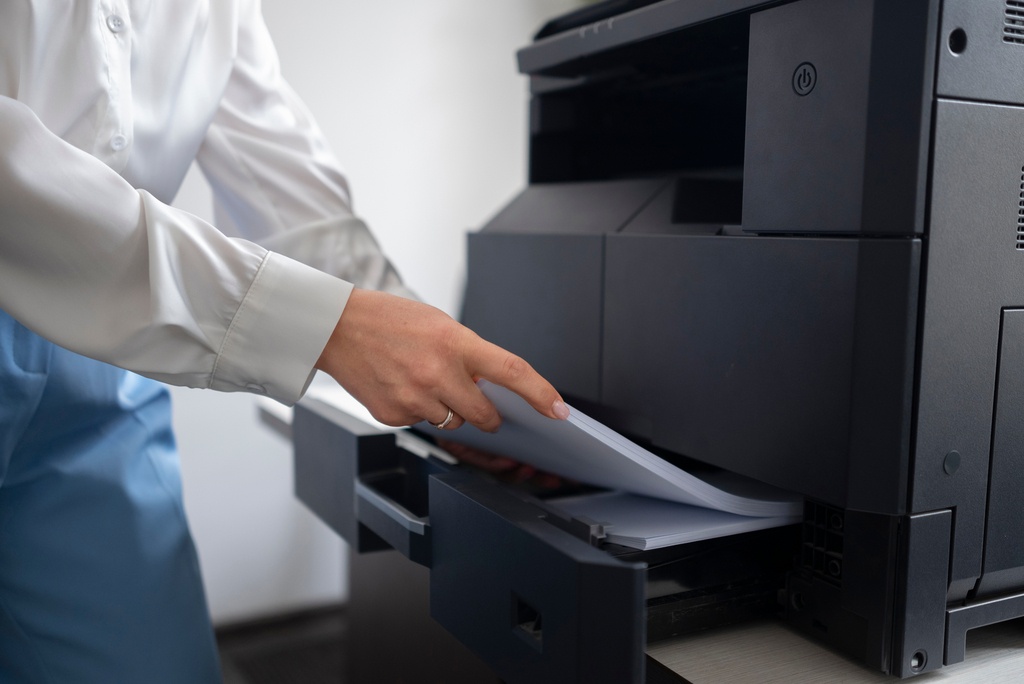 Office employee loading paper into a rented multifunction copier